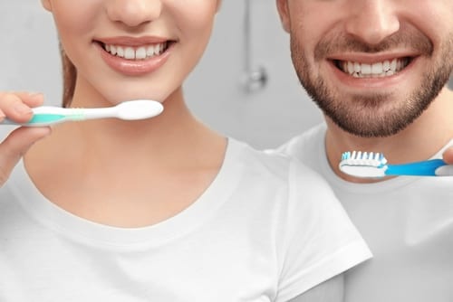 young happy couple brushing teeth in bathroom-img-blog