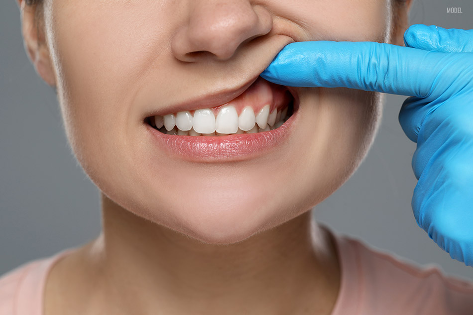 Woman showing healthy gums on gray background, closeup